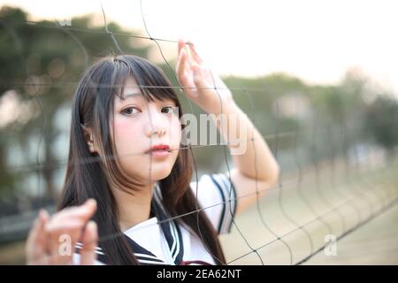 Ritratto di bella ragazza giapponese alta asiatica uniforme cercando con rete Foto Stock