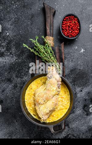 Unches di coniglio arrosto in padella con verdure stufate. Sfondo nero. Vista dall'alto Foto Stock