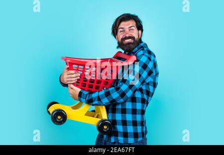 brutale uomo in camicia a scacchi ha barba lunga portare carrello, nero venerdì. Foto Stock