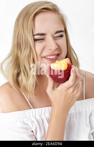 Ritratto di bella donna bionda con piacere mangiare nettarine Foto Stock