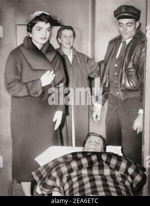 John F. Kennedy lascia il gurney dall'ospedale dopo la chirurgia spinale, come sua moglie Jacqueline si trova sopra di lui. STATI UNITI. 21 dicembre 1954 Foto Stock