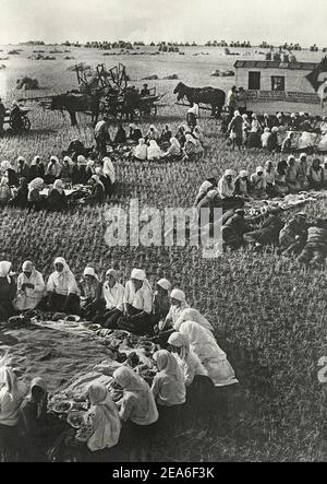 L'Unione Sovietica negli anni '30. Vita in una fattoria collettiva sovietica. Al raccolto, pranzo nel campo. Libro di propaganda sovietica. URSS, anni '30 Foto Stock