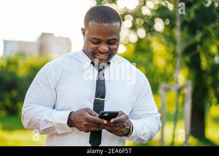 Ritratto di felice uomo d'affari afro-americano che sta usando lo smartphone. Foto Stock
