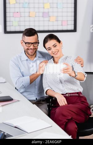 donna d'affari felice che prende selfie con il collega in occhiali Foto Stock