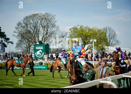 I jockeys al Grand National si fanno strada intorno alla precorsa dell'anello della parata che si tiene annualmente all'Ippodromo di Aintree, vicino a Liverpool, Inghilterra. Foto Stock