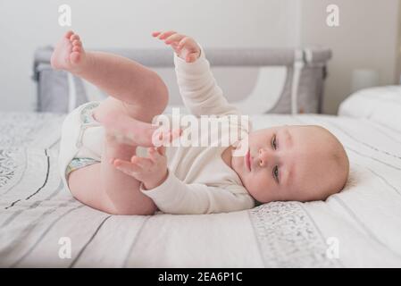 Un bambino carino che dorme su un letto enorme con bianco fogli Foto Stock