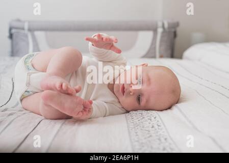 Un bambino carino che dorme su un letto enorme con bianco fogli Foto Stock