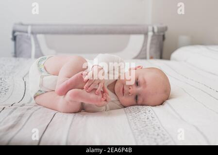 Un bambino carino che dorme su un letto enorme con bianco fogli Foto Stock