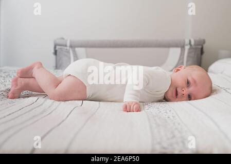 Un bambino carino che dorme su un letto enorme con bianco fogli Foto Stock