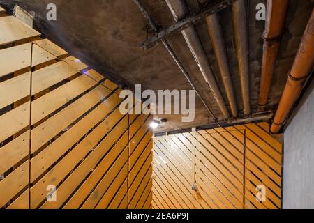 Interno del corridoio con pareti e porte in legno. Tubi del sistema di ventilazione dell'aria sul soffitto. Foto Stock