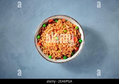 Tagliatelle con verdure in una ciotola, girata in alto su uno sfondo blu Foto Stock