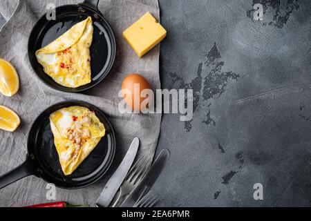 Omelette thailandese asiatica, peperoncino rosso fresco, carne di granchio bianca e marrone, limone, formaggio Cheddar, uova, su una padella di ferro, su sfondo grigio, vista dall'alto piatta Foto Stock