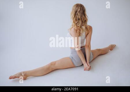 Vista posteriore di una ginnastica femminile che si divide con lei mani dietro la schiena Foto Stock