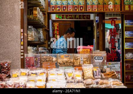 Taipei, Taiwan. 8 febbraio 2021. Un venditore di strada che indossa una maschera di vendita stagionale Lunar New Year sundries, compresi noci, frutta secca, e carne a scatti. Il mercato lunare di Capodanno di Taipei su Dihua Street sara' cancellato a causa di problemi relativi al COVID-19. Credit: SOPA Images Limited/Alamy Live News Foto Stock