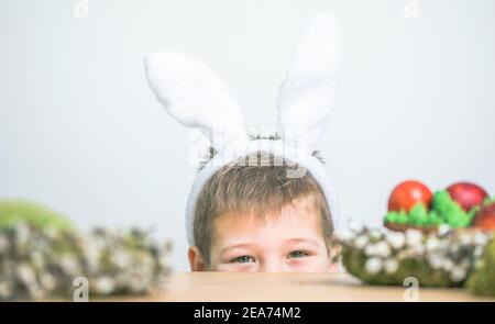 Divertirsi con la caccia all'uovo di Pasqua. Bambino che indossa orecchie conigliate il giorno di Pasqua Foto Stock