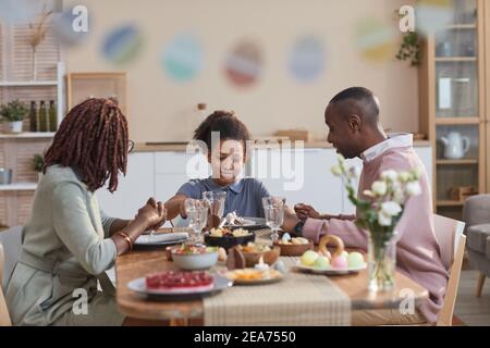 Ritratto della moderna famiglia afroamericana mentre si festeggia la pasqua a casa, concentrarsi su sorridente adolescente al centro, copia s. Foto Stock