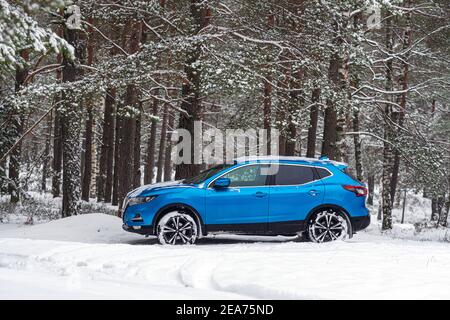 Riga, Lettonia - 30 gennaio 2021: Auto blu Nissan Qashqai parcheggiata nella foresta invernale Foto Stock