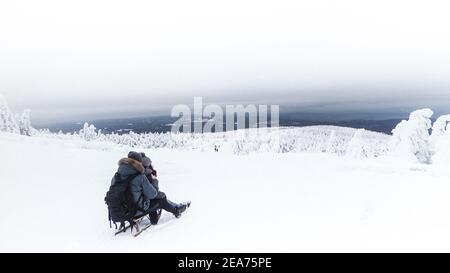 Giovane coppia romantica che scivola su una slitta nella neve a Brocken Harz, Germania Foto Stock