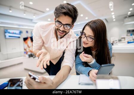 Coppia che mette a confronto quale smartphone è migliore. Uomo punta allo smartphone nelle sue mani. Foto Stock