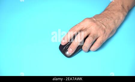 Isolato su sfondo bianco. La mano sinistra del vecchio uomo tiene il mouse del computer wireless sul tavolo. Fare clic e spostare Foto Stock