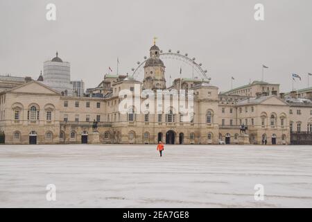 Un uomo cammina attraverso una parata coperta di neve delle Guardie a Cavallo Londra come Storm Darcy porta temperature gelide nel Regno Unito Foto Stock