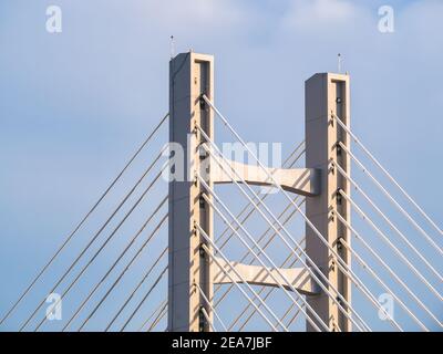 Struttura a ponte con fili in acciaio. Primo piano con la struttura metallica di un moderno ponte sospeso contro il cielo blu. Foto Stock