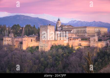 Vista classica con il vivace tramonto del Palazzo Carlo V, l'iconica Alhambra e le montagne della Sierra Nevada dal Mirador de San Nicolas nella vecchia albaicin Foto Stock