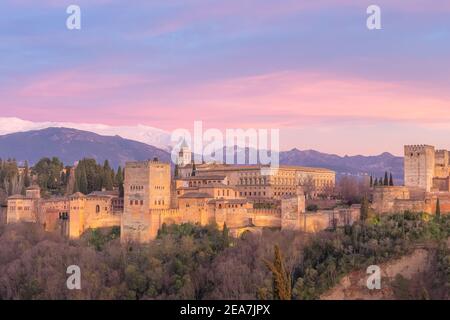 Vista classica con il vivace tramonto del Palazzo Carlo V, l'iconica Alhambra e le montagne della Sierra Nevada dal Mirador de San Nicolas nella vecchia albaicin Foto Stock