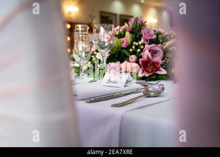 Ambiente per la colazione di nozze con il biglietto d'auguri in cima tavolo in attesa di arrivo con sposa e rose rosa e. bicchieri scintillanti di champagne Foto Stock