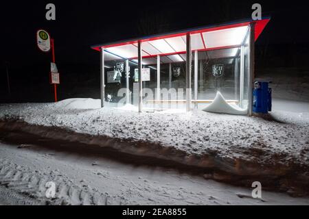 Himbergen, Germania. 8 febbraio 2021. Una fermata dell'autobus innevata si illumina nelle prime ore del mattino. Credit: Jonas Walzberg/dpa/Alamy Live News Foto Stock