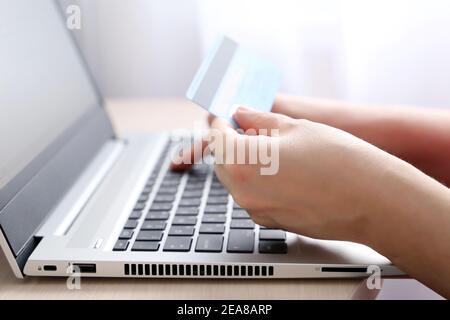 Donna che tiene tipi di carta di credito sulla tastiera del computer portatile. Concetto di acquisto e pagamento online, transazioni finanziarie Foto Stock