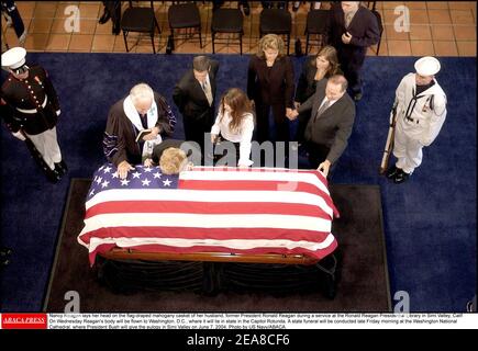 Nancy Reagan pone la testa sulla casetta di mogano drappeggiato con bandiera di suo marito, l'ex presidente Ronald Reagan durante un servizio alla Biblioteca presidenziale Ronald Reagan a Simi Valley, California. Mercoledì il corpo di Reagan sarà volato a Washington, D.C., dove giocherà nello stato della Capitol Rotunda. Un funerale di stato sarà condotto a fine Venerdì mattina presso la Cattedrale Nazionale di Washington, dove il presidente Bush darà l'elogio in Simi Valley il 7 giugno 2004. Foto di US Navy/ABACA. Foto Stock