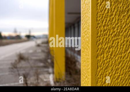 Bel calcestruzzo tonato giallo con sfondo sfocato di un abbandonato Luogo con vegetazione - Grunge luminoso sfondo di colore illuminante in grigio urbano c Foto Stock
