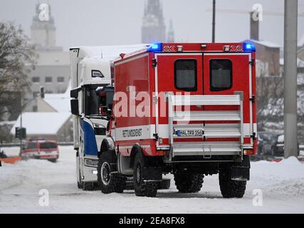 08 febbraio 2021, Sassonia-Anhalt, Halle (Saale): Un veicolo vigile del fuoco tira un camion su una collina nel centro di Halle/Saale. La forte caduta di neve porta a notevoli ostacoli su strade, ferrovie e sentieri. Foto: Hendrik Schmidt/dpa-Zentralbild/dpa Foto Stock