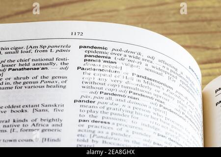 Primo piano del Dizionario delle Camere aperto alla definizione della parola 'Pandemic', su un vecchio tavolo di legno Foto Stock