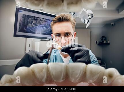 Denti di ritegno. Medico che guarda in bocca, controllo, esame dei denti. Utilizzo di strumenti e attrezzature professionali. Sanità e medicina, stomatologia, sentimenti di paziente. Guardare dall'interno dei denti. Foto Stock