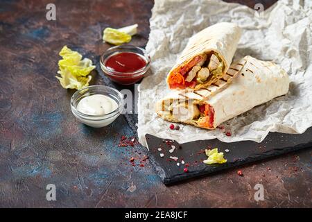 Shawarma orientale tradizionale con pollo e verdure, Doner Kebab con salse su ardesia. Fast food. Cibo orientale. Foto Stock