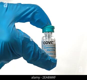 Tenendo in mano il flacone di vaccino con coronavirus con un guanto in lattice sfondo bianco Foto Stock