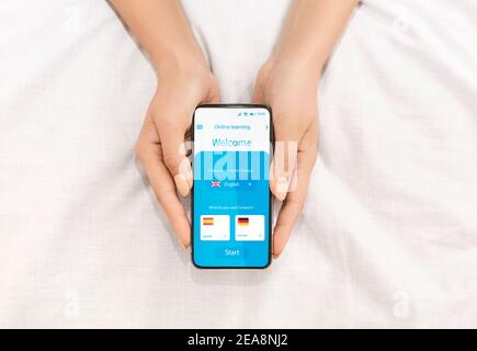 Unriconoscable Lady Learning Foreign Languages Online in Mobile Application ON Smartphone Foto Stock
