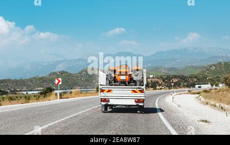 Transport and deliver a new or broken tractor to the farm in a small truck. Agriculture business and machine industry Foto Stock