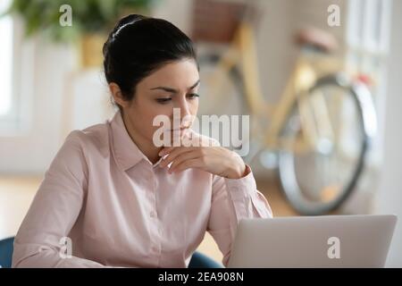 Seria giovane donna indiana che lavora al computer a casa Foto Stock