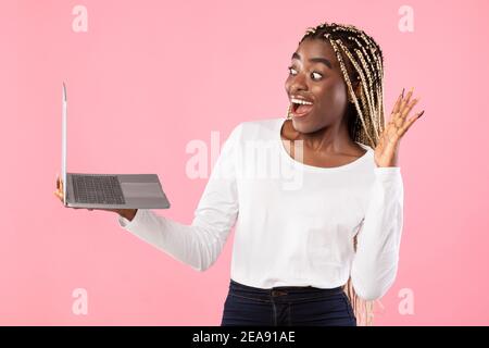 Donna nera che ha una videocamera che usa il laptop che ondeggiava la mano Foto Stock