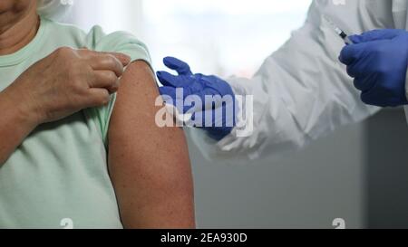 Medico che tiene la siringa e che usa il cotone prima di fare l'iniezione al paziente. Vaccinazione e prevenzione contro l'influenza o pandemia virale. Foto Stock