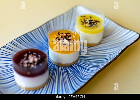 un trio di mini cheesecake dai colori scuri a quelli chiari servito su un piatto Foto Stock