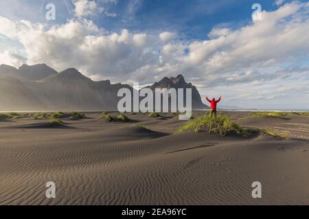 Escursionista che si affaccia sul Vestrahorn / Vesturhorn, fatto di gabbro e rocce granofire, parte della catena montuosa di Klifatindur a Stokksnes, Islanda Foto Stock