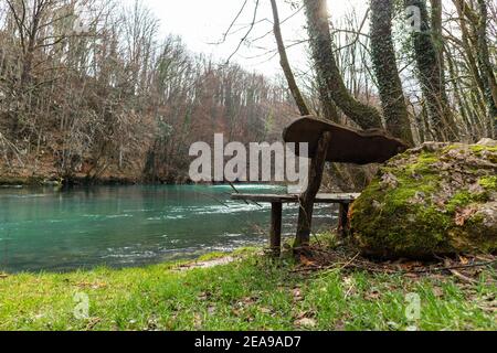 Panca di legno sul bordo del fiume Slunjcica, situato nella regione di montagna della Croazia Foto Stock