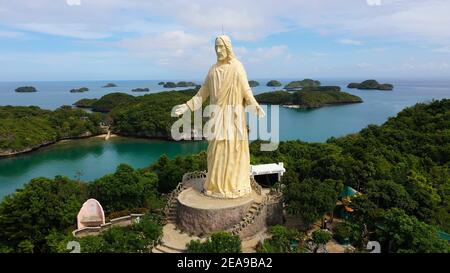 Statua di Gesù Cristo in pellegrinaggio isola in Cento Isole Parco Nazionale, Pangasinan, Filippine. Vista aerea del gruppo di piccole isole con spiagge e lagune, famosa attrazione turistica, Alaminos. Foto Stock