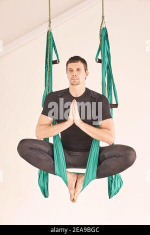 Persona maschile fare amaca yoga lezione di esercizio. Meditazione in aria calma Foto Stock