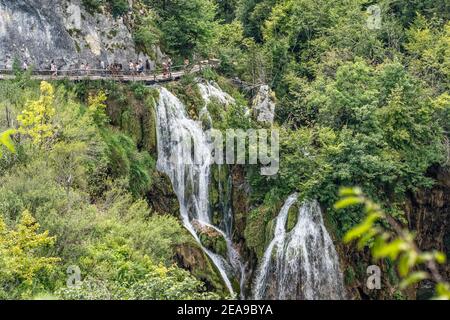 Plitvice, Croazia - 11 agosto 2020: I turisti camminano attraverso la cascata nel parco del lago Foto Stock