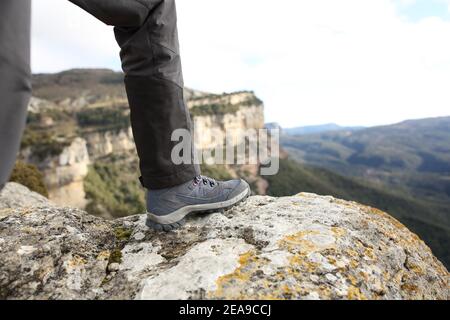 Primo piano di uno scarpone da trekking nella parte superiore di una scogliera in montagna Foto Stock